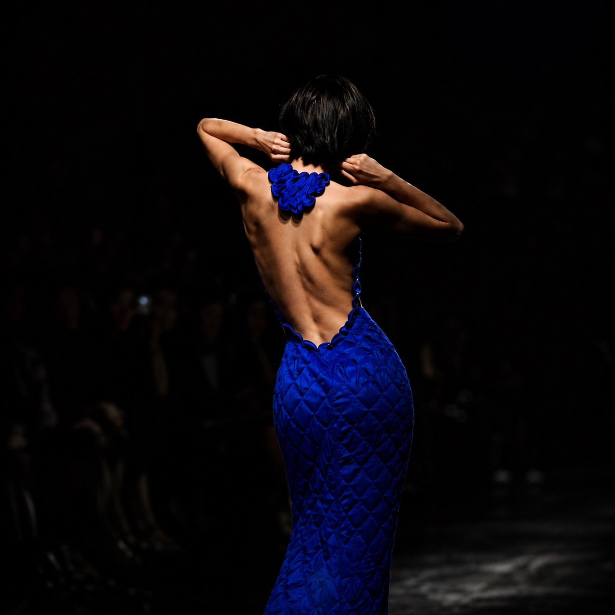 A woman in a dark blue dress in a moody editorial portrait.